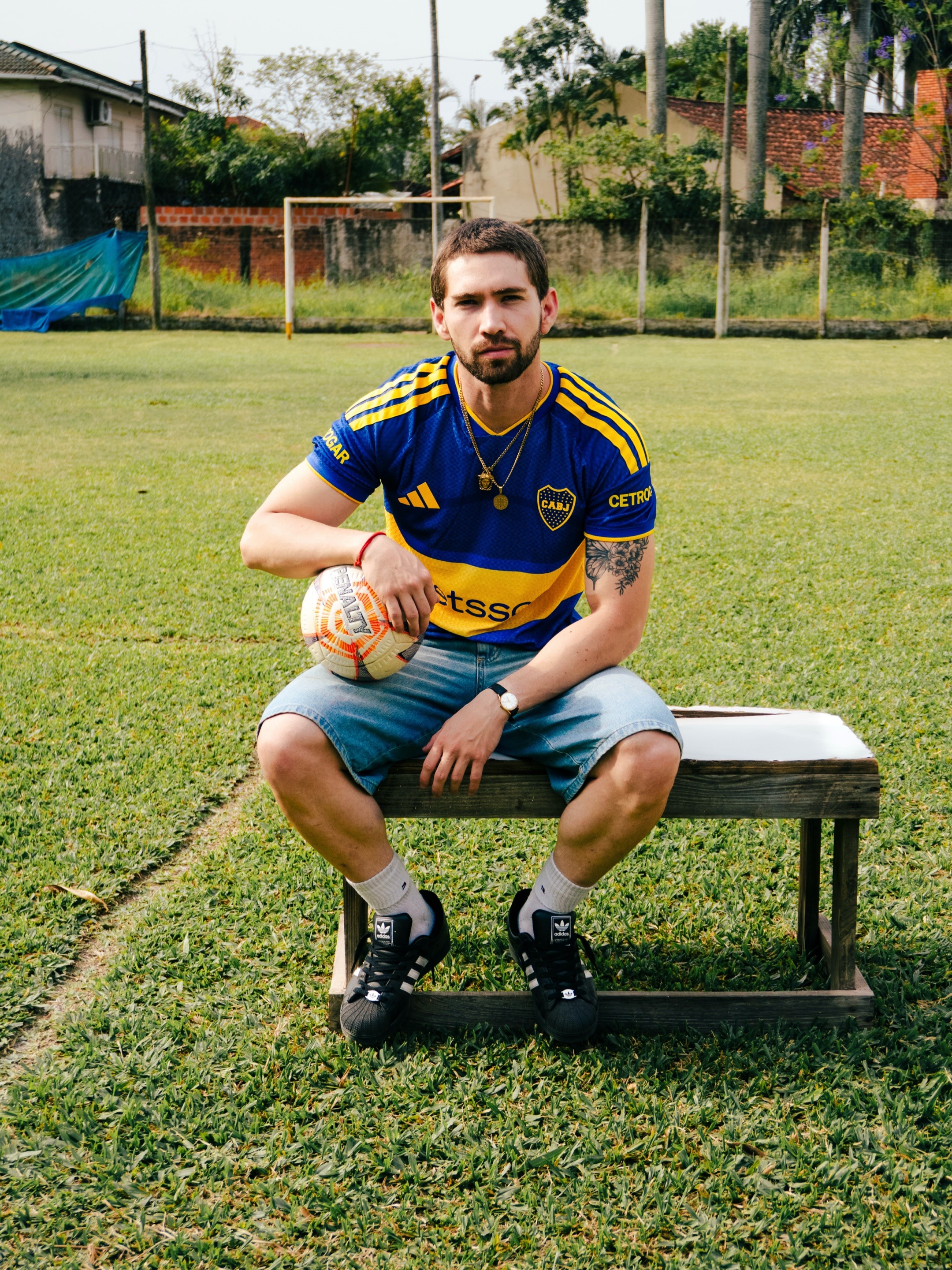 Retrato en una cancha con camiseta azul y amarilla de Boca y una pelota